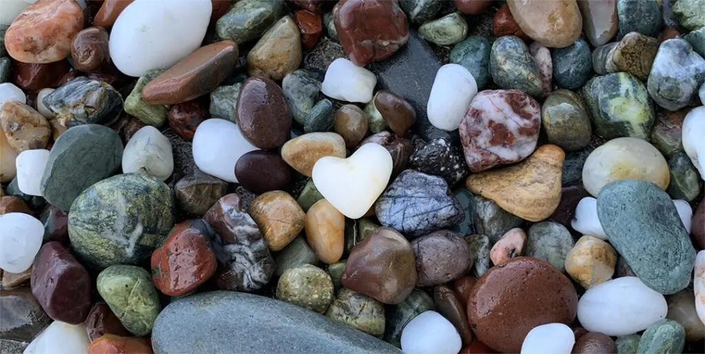 White heart-shaped rock on pile of colorful rocks
