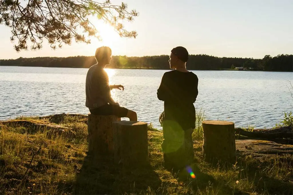 two people talking beside a lake